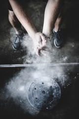 cropped shot of power lifter clapping hands with talc before training