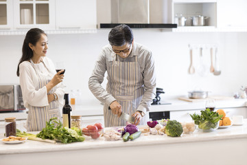 Happy mature couple cooking in kitchen