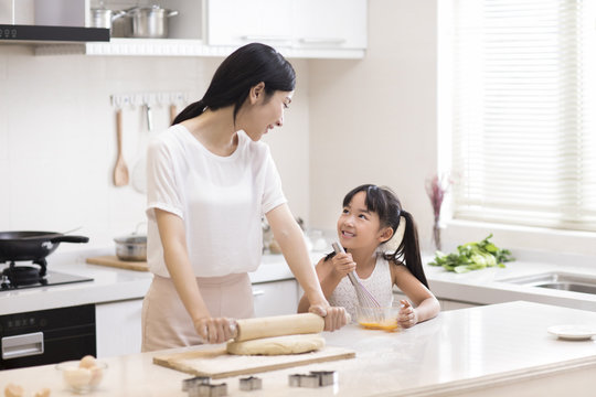 Happy Little Girl And Mother Cooking In Kitchen