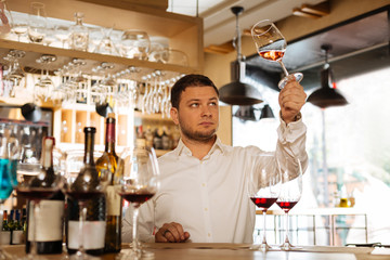 Perfect colour. Nice smart man looking at the glass while checking the colour of wine