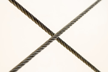 Crossing of shiny steel cables on a white background. Symmetry in the installation of steel structures. The application of steel crosses to the cross.