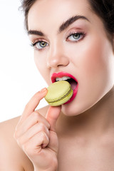 attractive stylish woman biting green macaron, isolated on white