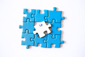 White puzzle piece on top of a blue puzzle