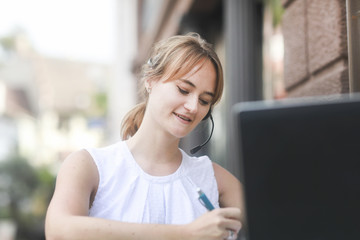 Junge Frau mit headset arbeitet draussen