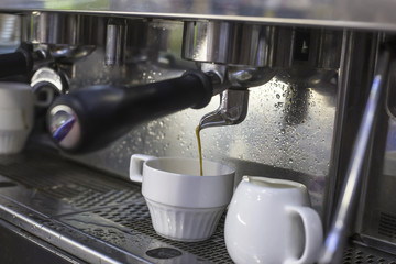 A coffee machine prepares two espresso in two glass cups in a cafe. The work of the coffee machine. Culture of coffee making in the city