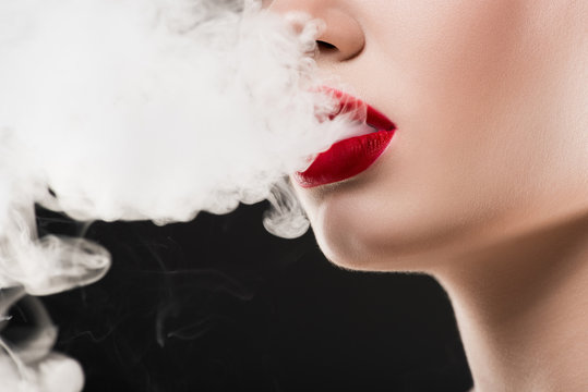 cropped view of smoking woman blowing smoke, isolated on grey