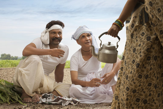 Two farmers sitting in field drinking tea 