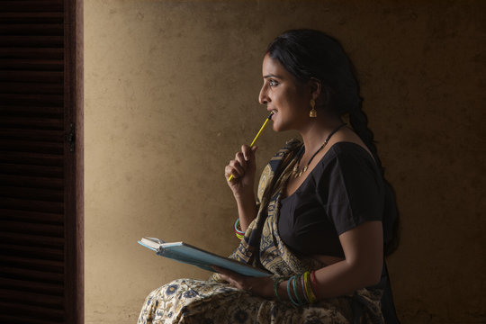 Woman wearing sari holding notebook and pencil