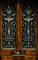 Old wooden door with stylish  forged pattern and metallic handle