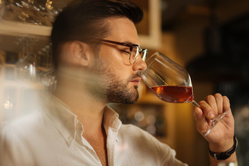 Best drink. Portrait of a handsome good looking man smelling wine before trying its taste
