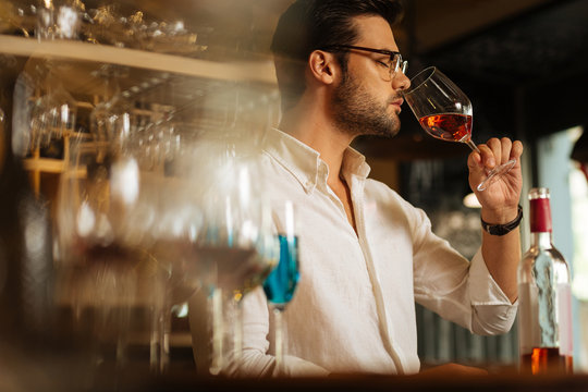 Feeling the taste. Nice serious man putting a glass to his nose while wanting to try delicious wine