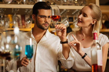 Beautiful shade. Handsome smart man looking at the colour of wine while showing it to the guest