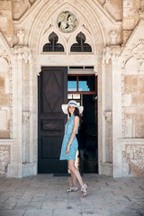 Fototapeta na wymiar Brunette girl in blue summer dress walking on old narrow street