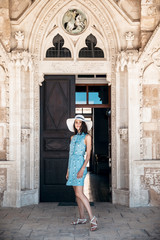 Fototapeta na wymiar Brunette girl in blue summer dress walking on old narrow street