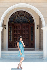 Brunette girl in blue summer dress walking on old narrow street