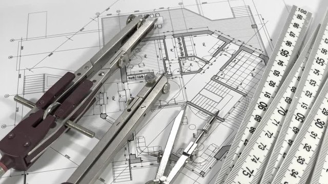 Blueprints - architectural drawings, yardstick - folding ruler and compass smoothly rotate on the surface of the architectural plan of a modern house	