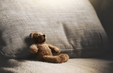 Teddy bear sitting down on sofa in retro filter, Lonely teddy bear sitting alone on couch in living...