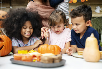 Young kids carving Halloween jack-o&#39;-lanterns