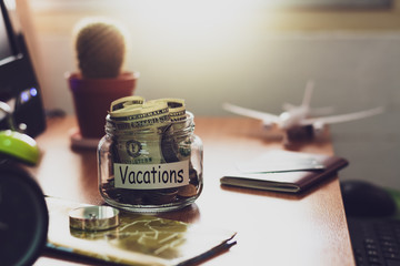Vacation budget concept. Money for vacations savings in a glass jar on working desk.