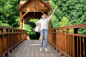 Fototapeta na wymiar Jumping woman. Happy retired woman feeling extremely happy while jumping enjoying nice popular eco tourism