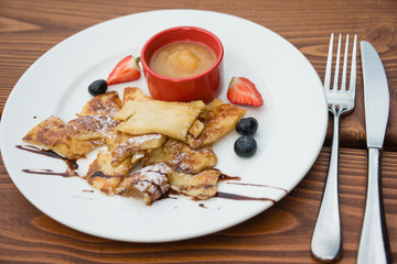 Cut-up and sugared pancake with apple puree and forest fruits