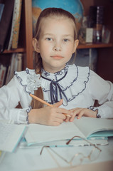 A little schoolgirl sits at a desk