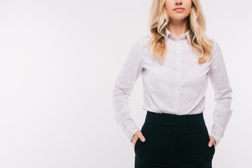 cropped image of businesswoman standing with hands in pockets isolated on white