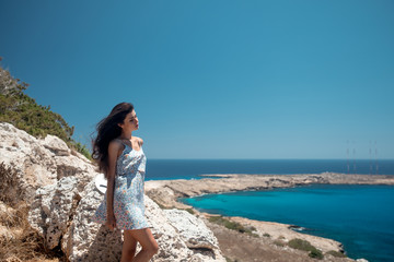 Fototapeta na wymiar Girl on the edge of a cliff overlooking the sea in a dress