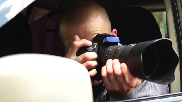 Young Male Detective Took A Photo Of Evidence On His Camera With A Zoom Lens Sitting In The Car In The Summer