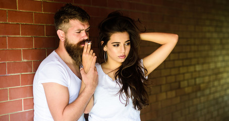 Break or pause for smoking. Share single cigarette. Couple find place to hide from witnesses, smoking cigarette in tranquility. Couple in love hugs while smoking cigarette brick wall background