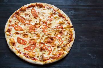 pizza with cheese and tomatoes on dark table