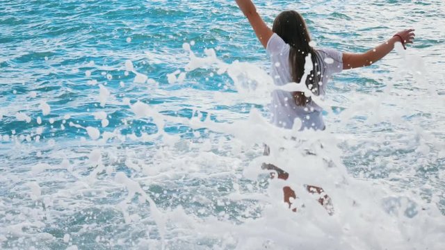 Beautiful young girl having fun playing with the waves of the amazing sea