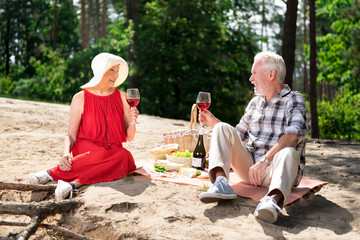 Romantic picnic. Couple of good-looking pensioners feeling relaxed while having very cute romantic...