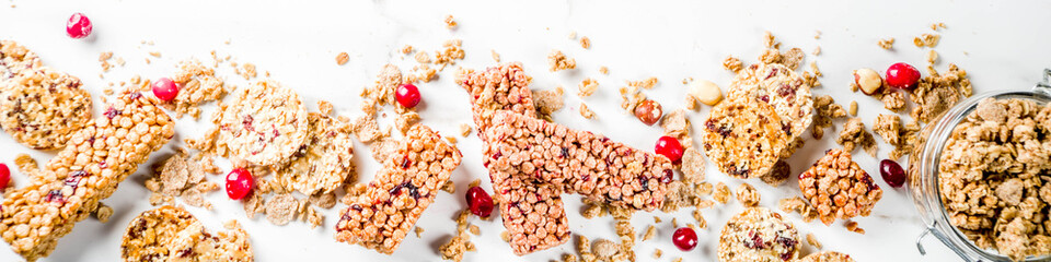 Multi grain granola muesli bar. Healthy sweet food, diet snack, with dried berries, nuts, cereals and honey. On a white marble background, top view copy place for text. banner