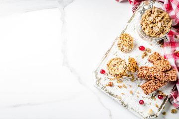 Multi grain granola muesli bar. Healthy sweet food, diet snack, with dried berries, nuts, cereals and honey. On a white marble background, top view copy place for text.