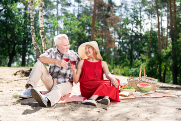 Wine and fruits. Elderly wife and husband feeling memorable and relaxed while drinking wine and eating fruits on the beach