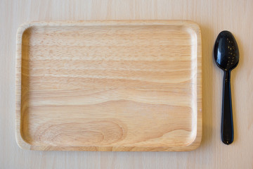 Black spoon in wooden plate