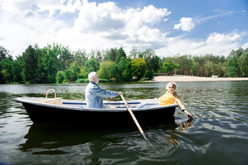 Obraz premium Excited woman. Beaming elderly woman wearing sunglasses and head band feeling excited having boat ride