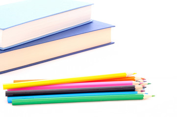 back to school, minimal background, pile of colored pencils and books on the white desk