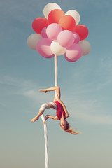 Girl does tricks on the canvases in the air. Balloons keep the canvas in the air.