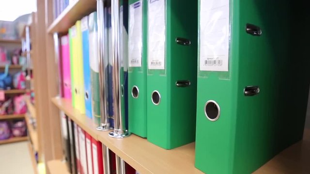 Female hand taking folder from shelf in stationery store