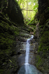 Cascade falls over mossy rocks. Spring in forest.magic lightnings.Deep forest athmosphere.