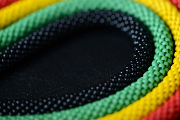 Fragment of a beaded necklace in Jamaican style on a dark background close up