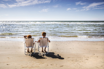 Netherlands, Zandvoort, boy and girl sitting on chairs on the beach