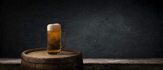 Oktoberfest beer barrel and beer glasses with wheat and hops on wooden table