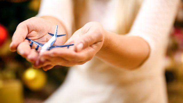 Closeup image of young woman holding small toy airplane in hands. Concept of winter holidays travelling