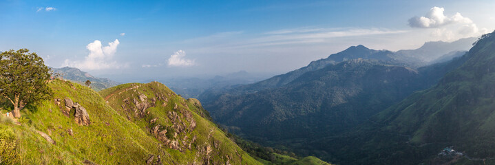 Experience serenity with this breathtaking panoramic view of a mountain in Sri Lanka against a blue sky with fluffy clouds. Perfect for travel, meditation, and wanderlust concepts