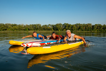Joyful friends, a SUP surfers relax on the big river