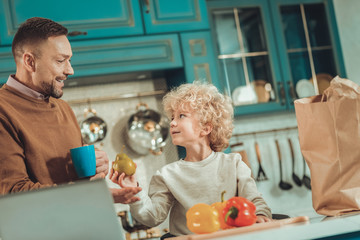 Family time. Happy father and the child looking at each other while cooking together
