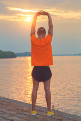 Young man stretching on a fence after jogging / excercising.